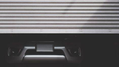 The bottom half of a silver car is seen as a garage door opens in front of it