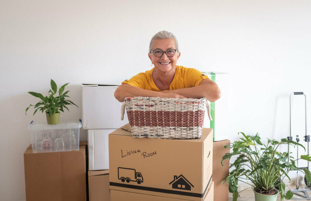 An older woman posing behind packed boxes.