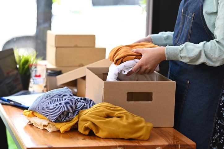 Seasonal clothing being packed into a box for storage.