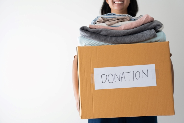 Smiling woman holding a box of clothes for donation.